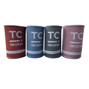 4 stubby holders in burnt orange, blue, grey and pink with the Tom Curtain logo on it (TC with a line and dot)