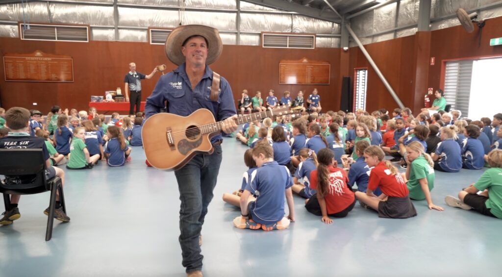 Singer songwriter with guitar at primary school assembly teaching the anti-bullying message.