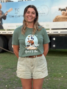 HeresToYouTeeAdult-front Tom Curtain crew member Hannah showcasing the front of the Here's To You Anniversary T-shirt