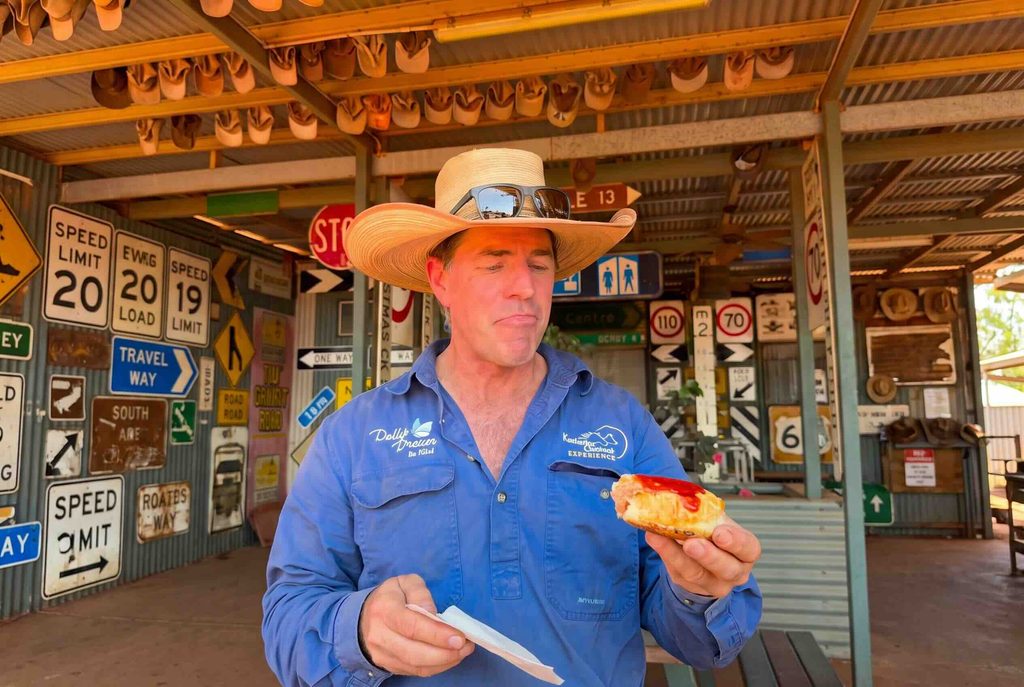 Tom Curtain on Tour eating a sausage roll at the sandfire roadhouse