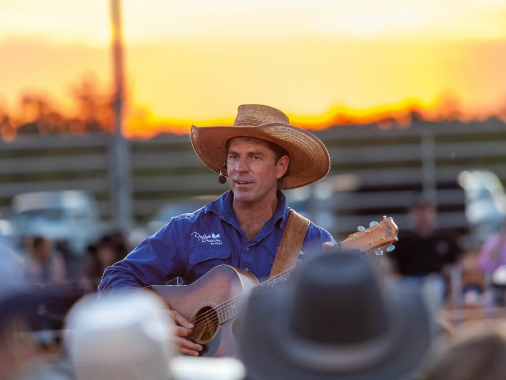 Tom Curtain singing to a crowd at sunset.